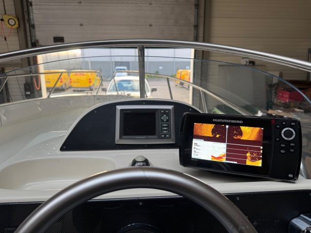 Het interieur van een boot met een dashboard en navigatieapparatuur.